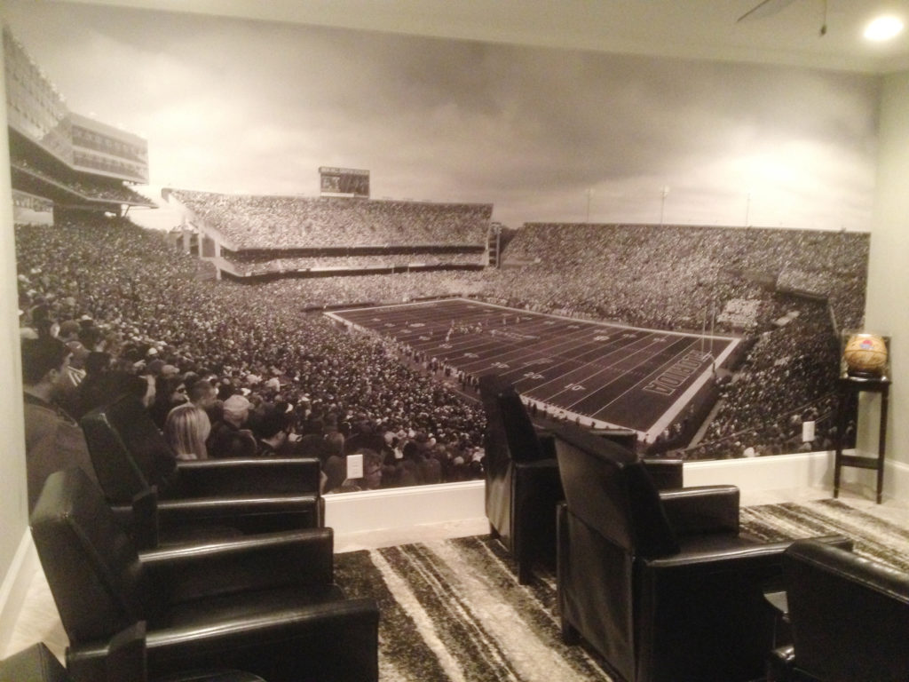 A media room with stadium seating deserves a wall mural that gives it a true stadium feel. We're guessing this man cave is very popular during football season (and all year long).