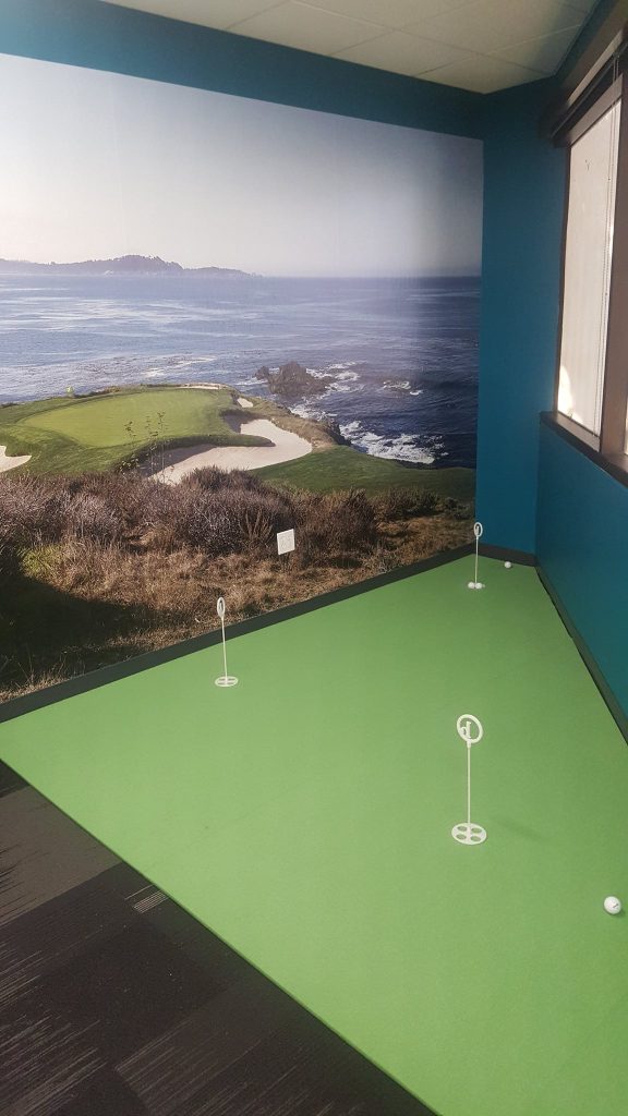 A golf course mural featuring the famed links at Pebble Beach give this corner of the office a 3 hole putting green.